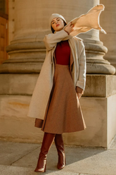 a lady in a red sweater, a beige coat and a brown plaid skirt